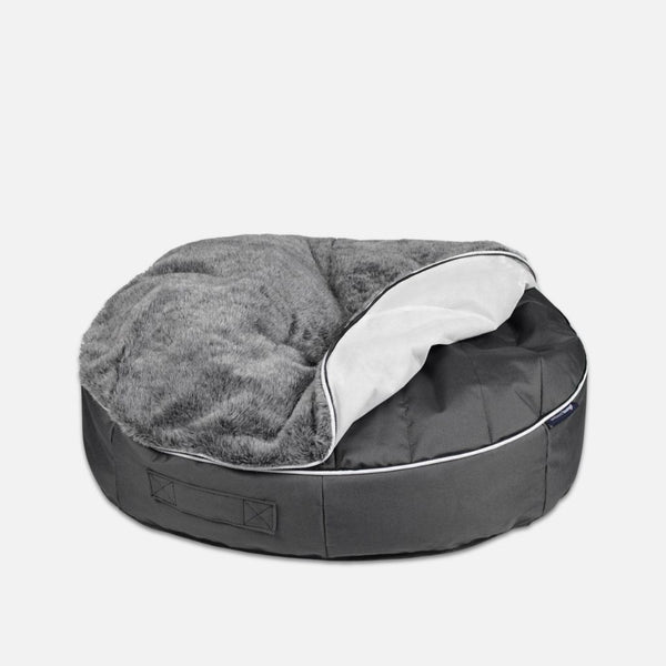 Hringlaga, dökkgrátt Ambient Lounge rúmföt með mjúku, flottu áklæði sem er að hluta opið og afhjúpar létt innra fóðring. Rúmið er með handfangi á hliðinni og er staðsett á hvítum bakgrunni.